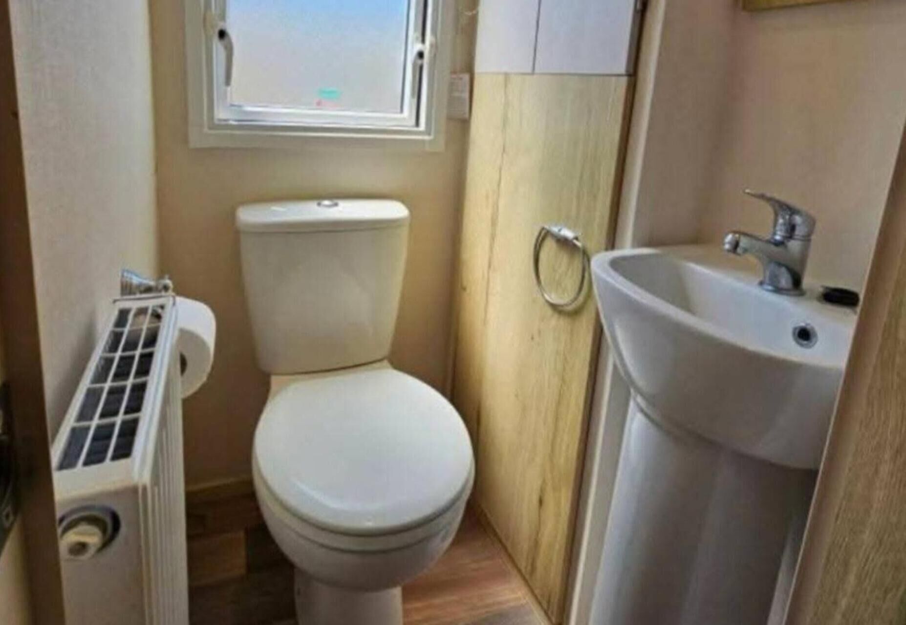 Pieni kylpyhuone, jossa on wc, pesuallas ja ikkuna wc:n yläpuolella.
