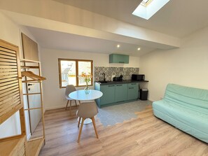 A compact living space with a dining area, kitchenette, and a sofa. - Viel Antibes - studio rénové & plein de charme (Antibes)