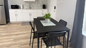 A modern kitchen with white cabinets, a black dining table, and a potted plant. - Modern Open Studio - 3 Beds - 2 queens & 1–Full Sleeps 6- Near Local Attractions (Marksville)
