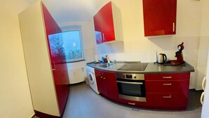 A compact kitchen with a built-in oven, a microwave, and a sink. - Room "white" in shared flat - central & quiet - VW, Autostadt, VfL parking lot and WLAN (Wolfsburg)
