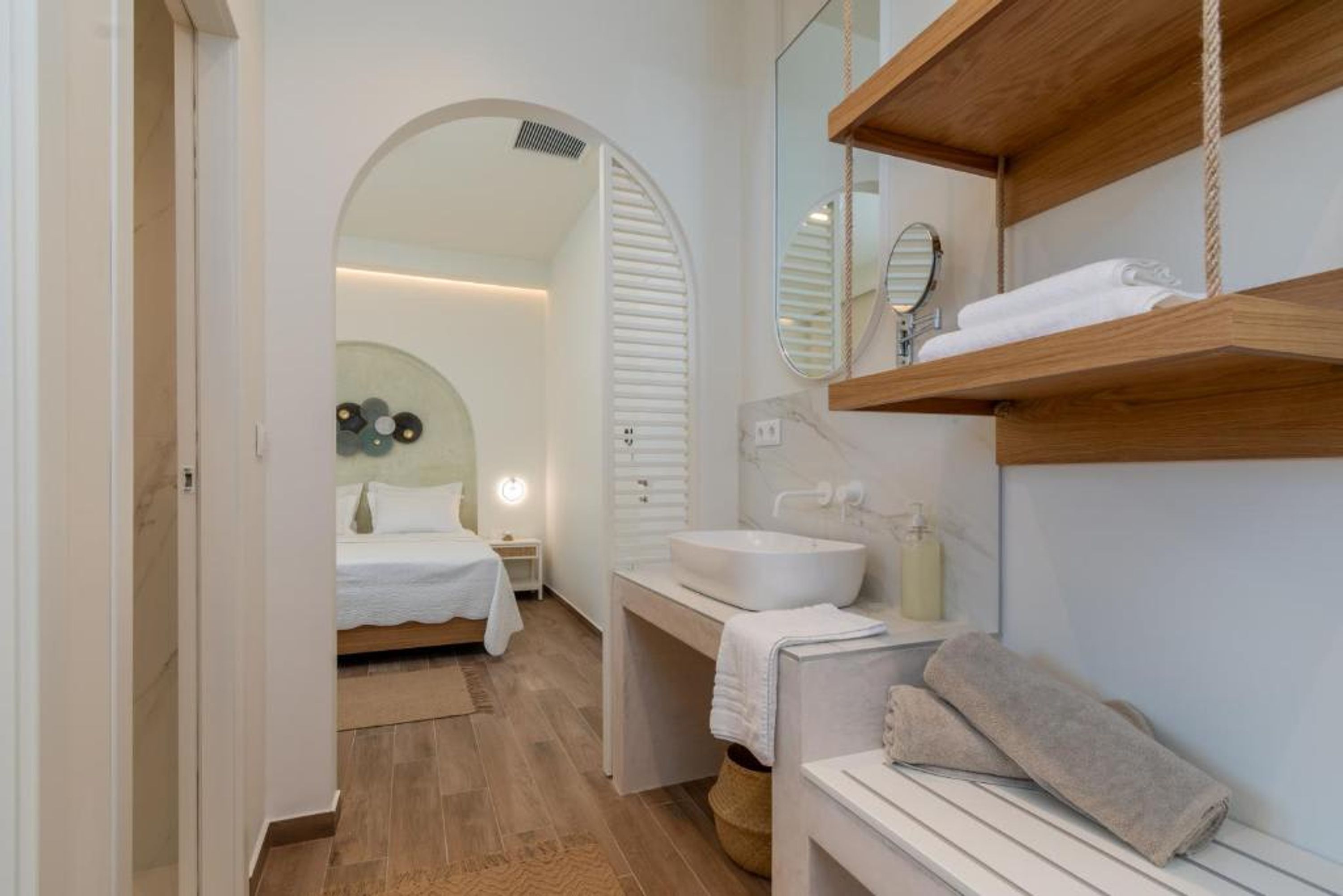 Een moderne badkamer met een houten wastafelmeubel, een grote spiegel en een witte wasbak.