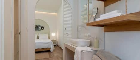 A modern bathroom with a wooden vanity, a large mirror, and a white sink.