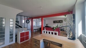 Un'ampia zona giorno con pavimento in legno, una parete decorata di rosso e una scala che conduce a un altro piano.