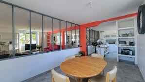 A modern kitchen with built-in appliances, a dining area with a wooden table and chairs, and a large window with a view of the outdoors. - Spacious, elegant townhouse a stone's throw from the historic center (Quimper)