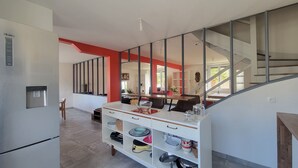 Una cucina moderna con un dispenser d'acqua, una zona pranzo con tavolo e sedie, e una scala che conduce a un altro piano.