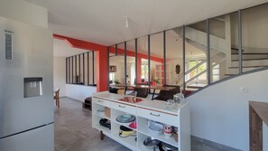 Eine moderne Küche mit Wasserspender, ein Essbereich mit Tisch und Stühlen sowie eine Treppe zu einer weiteren Ebene.