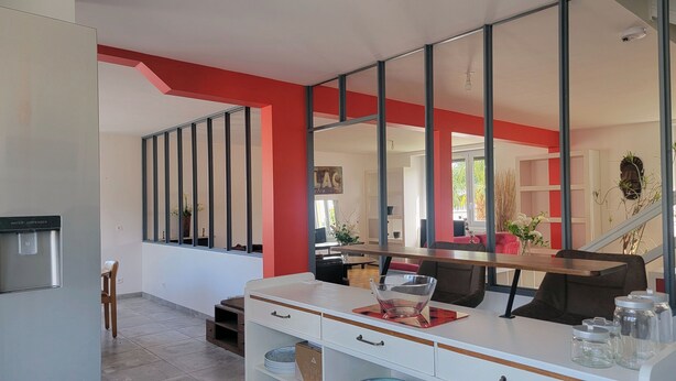 Una cucina moderna con un erogatore d'acqua, una zona pranzo con tavolo e sedie, e un grande specchio che riflette l'ambiente.