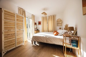 Ein Schlafzimmer mit Bett, einem Holzschrank, einem Nachttisch mit Lampe und einem Fenster mit Vorhängen.