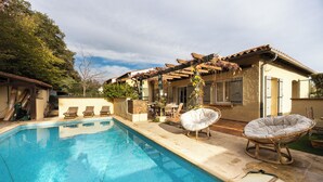 A swimming pool with lounge chairs, a pergola, and a house with a tiled roof. - Magnificent house close to the beach (Perpignan)
