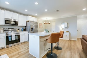 A modern kitchen with white cabinetry, stainless steel appliances, a central island, and bar stools. - Relax and Revive in new 3 BDRM /2BA Family Friendly Home in San Angelo. (San Angelo)