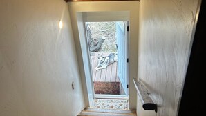 A wooden staircase leading to a door with a view of a dog outside. - Beautiful In Bigfork - Newly built Studio Apmt. (Bigfork)