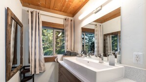 A modern bathroom with a large white sink, wooden ceiling beams, and a large mirror. - Beautiful In Bigfork - Newly built Studio Apmt. (Bigfork)