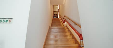 A wooden staircase with a red handrail leading to a room.