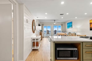 A modern kitchen with a large island, wooden flooring, and a view to the outside. - Pinnacle Port, C2-603 (Panama City Beach)