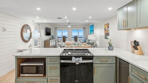 Una cocina moderna con una isla central, microondas integrado y vistas al exterior.