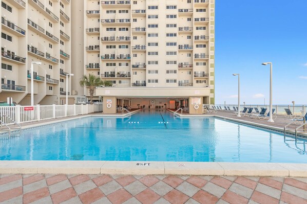 A swimming pool with a view of a tall building, a deck with lounge chairs, and a sign indicating a 3-star rating. - Pinnacle Port, C2-603 (Panama City Beach)