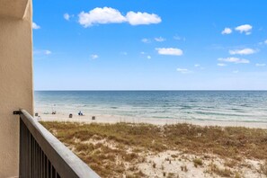 A beach view from a balcony with a clear sky, sandy beach, and sparse vegetation. - Pinnacle Port, C2-301 (Panama City Beach)