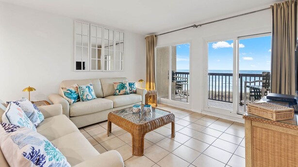 Een ruime woonkamer met een bank, salontafel en een balkon met uitzicht op zee.