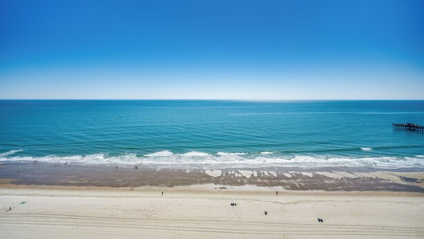 A beach with a pier extending into the ocean, sandy shore, and clear blue sky. - ALL NEW Family Jewel Myrtle Beach (MYRTLE BEACH)