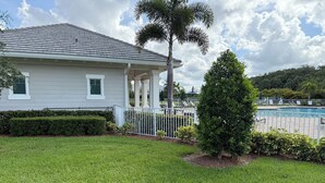 A house with a covered porch, a swimming pool, and well-maintained lawn.