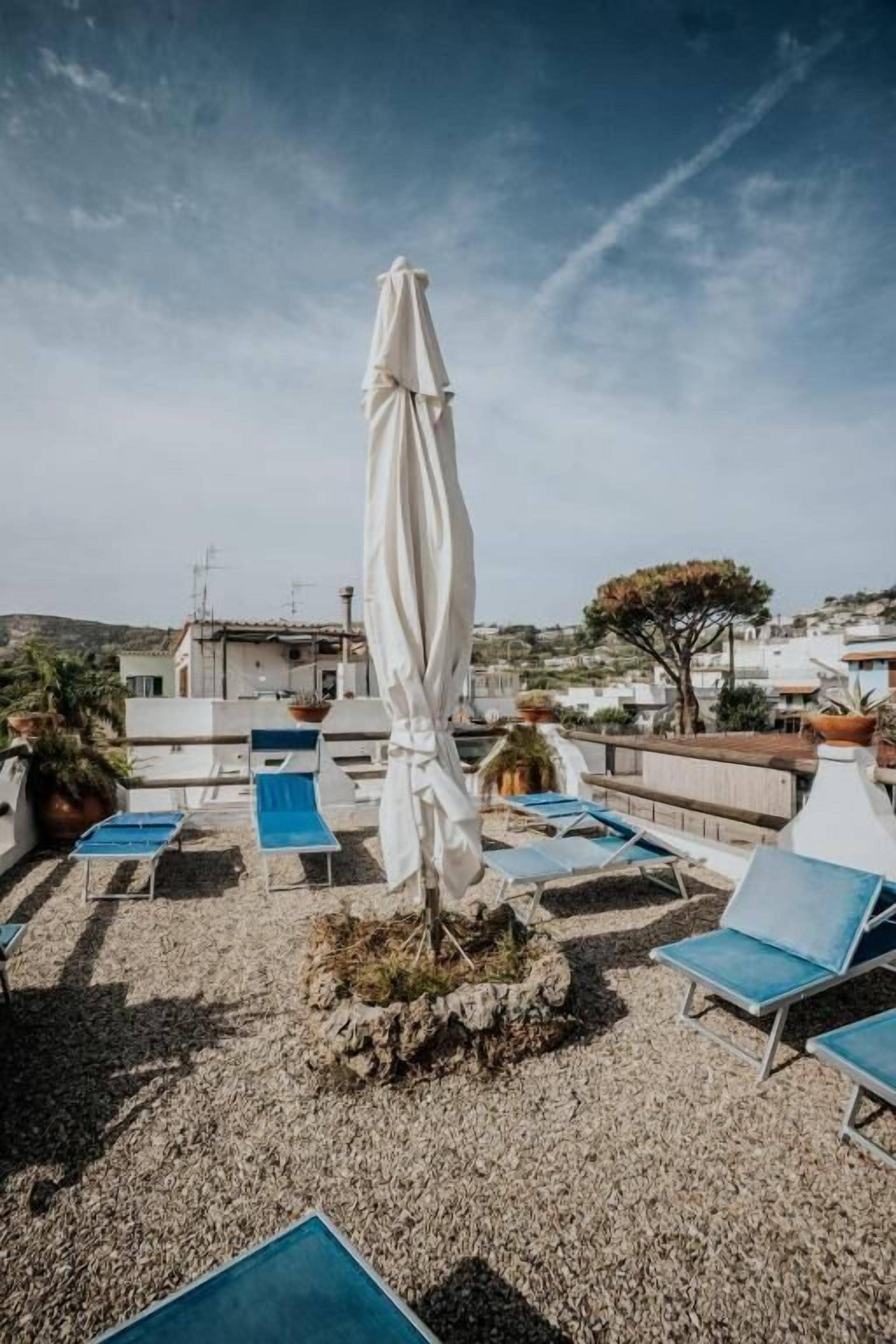 Una terrazza panoramica con poltrona lounge e un ombrellone bianco.