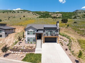 A modern two-story house with a garage, a covered porch, and a landscaped front yard. - Eden's Basecamp |Hot Tub |Firepit | Kayaks & Bikes (Eden)