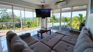 Una sala de estar moderna con un sofá grande, un televisor de pantalla plana y un balcón con vistas.