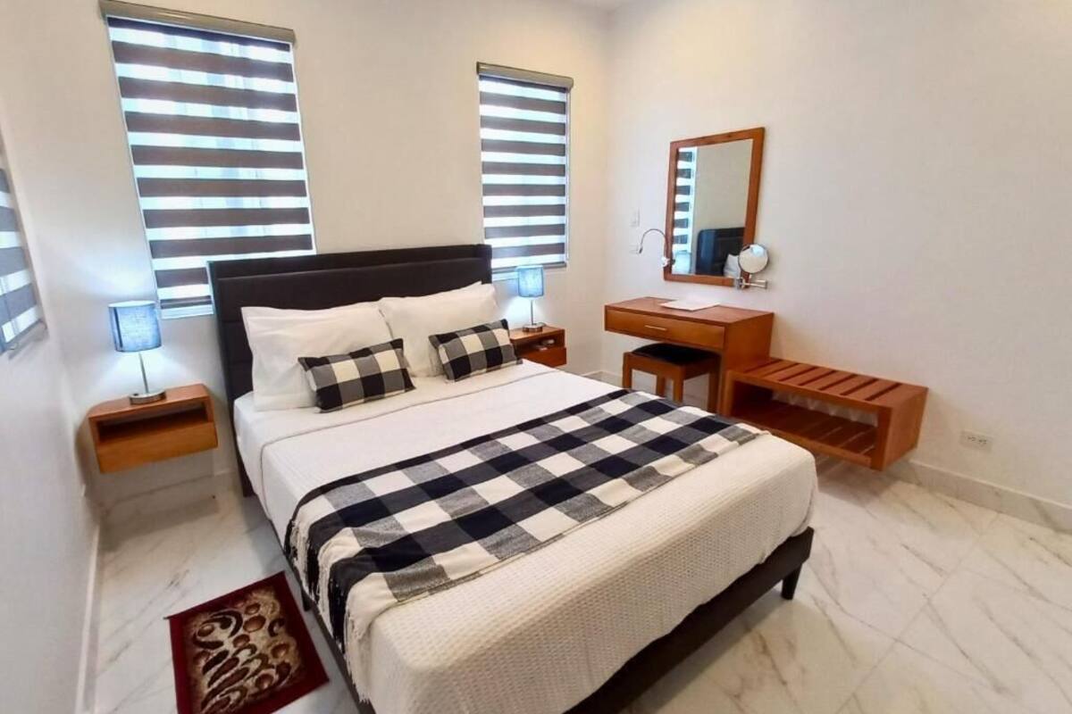 Un dormitorio con cama, mesitas de noche, tocador, espejo y una banca.