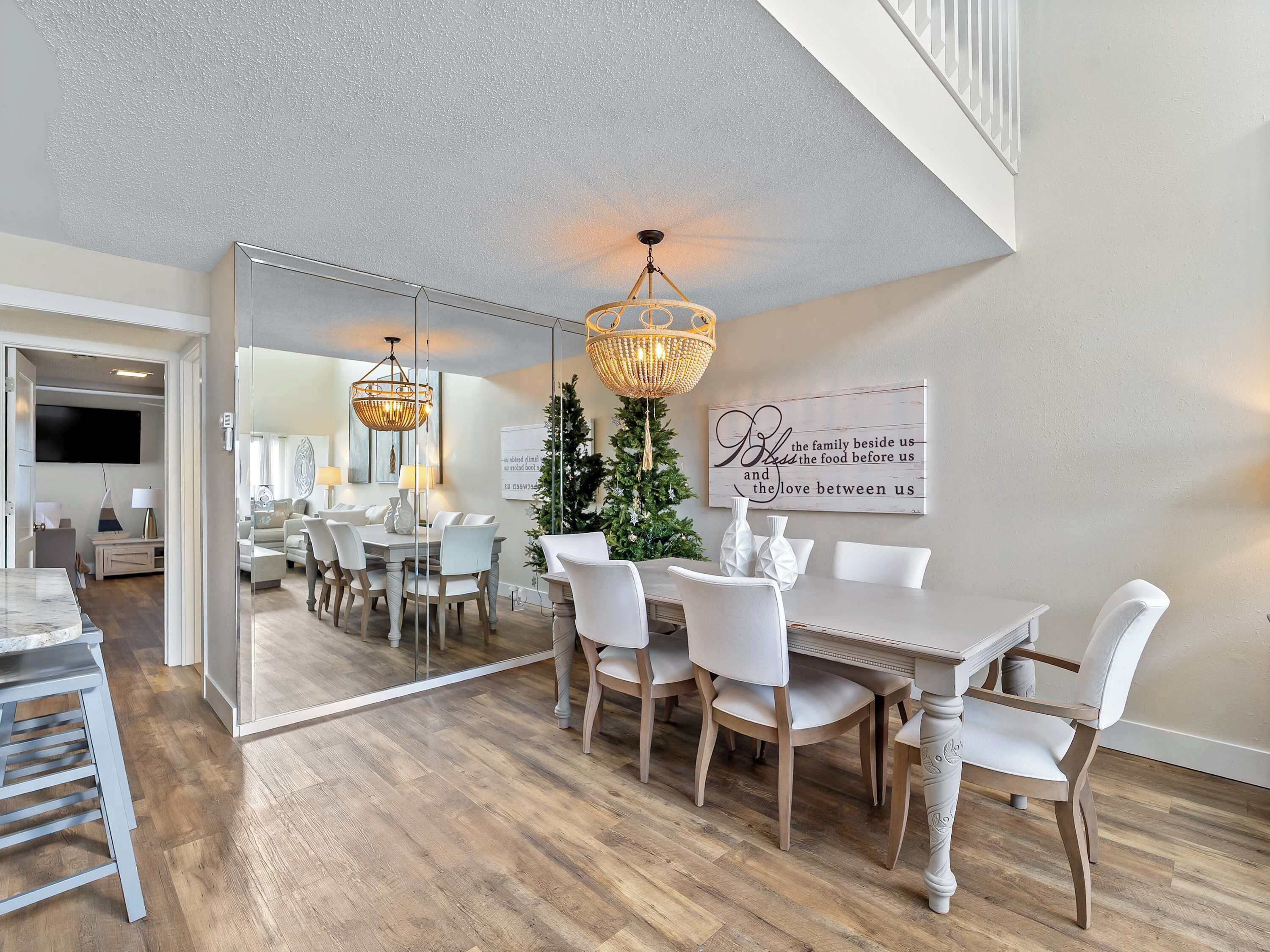 A dining area with a large mirror, a chandelier, and a Christmas tree.