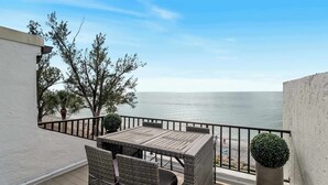 A balcony with a table and chairs, overlooking a body of water. - Gulf View Condo - Beach Access - Rooftop Deck (Englewood)