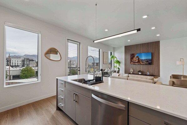 A modern kitchen with a large island, stainless steel appliances, and a view of the city. - Stylish 2-Bedroom, 2-Bath Salt Lake City Apartment with Balcony (Salt Lake City)