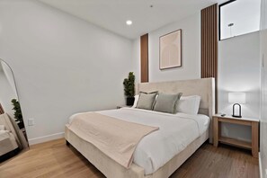 A modern bedroom with a large bed, bedside tables, a mirror, and a potted plant. - Stylish 2-Bedroom, 2-Bath Salt Lake City Apartment with Balcony (Salt Lake City)