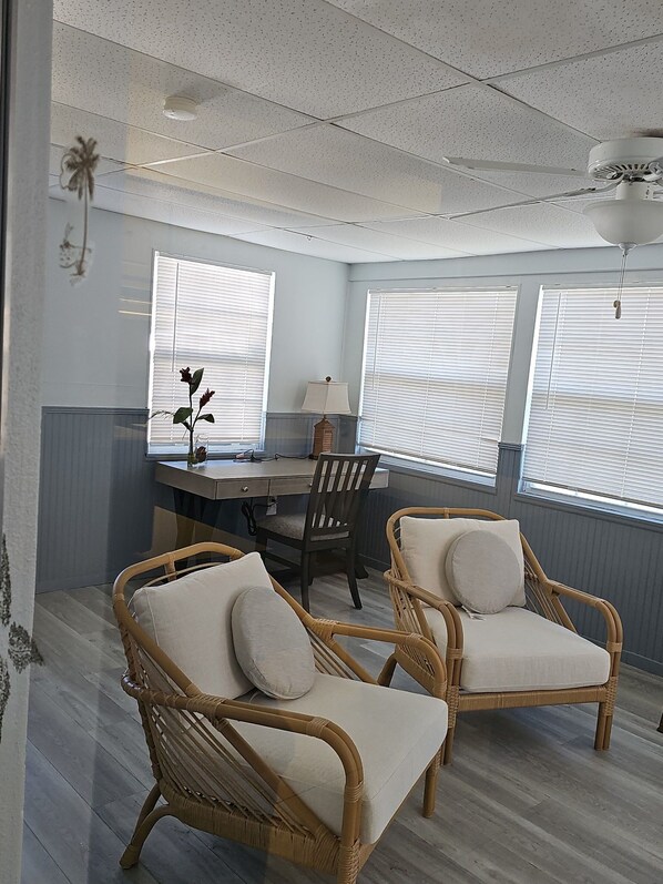 A room with a desk, two wicker chairs, a lamp, and three windows with blinds. - Serene 2-bedroom house with AC in charming North Port (North Port)