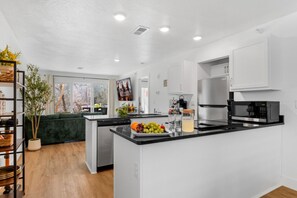 A modern kitchen with white cabinetry, a black countertop, and stainless steel appliances. - Spacious 2BR Condo Sleeps 8 w/ Patio, Indoor Pool, Gym and Resort Access (Branson)