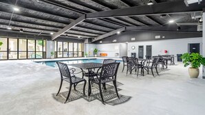 Un área de piscina interior con suelo de hormigón, sillas y mesas de metal.