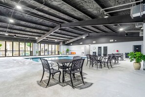 An indoor pool area with a concrete floor, metal chairs, and tables. - Spacious 2BR Condo Sleeps 8 w/ Patio, Indoor Pool, Gym and Resort Access (Branson)