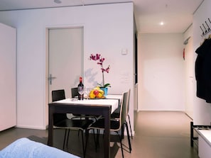 A small dining area with a table set for two, a bottle of wine, and a fruit bowl. - Apartment  by Interhome (Lucerne)