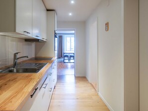Une cuisine moderne dotée d’un plan de travail en bois, d’un évier en acier inoxydable et d’armoires.