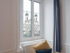 Una habitación con un ventanal grande, un radiador y dos almohadas.