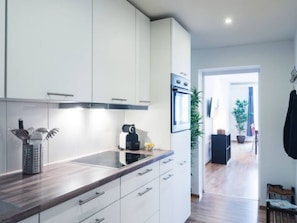 Una cocina moderna con armarios blancos, una campana extractora de acero inoxidable y un horno empotrado.