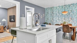 A modern kitchen with a central island, a dining area with wooden chairs, and a patterned wall. - Pet-Friendly Home - Sleeps 6 - Walkable Lakewood (Lakewood)