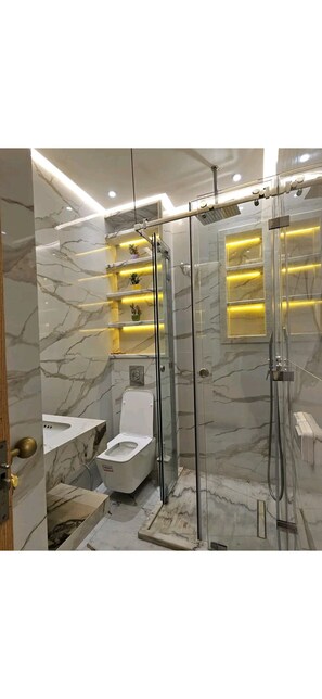 Ein Badezimmer mit einer Duschkabine, Marmorwänden und einer Toilette.