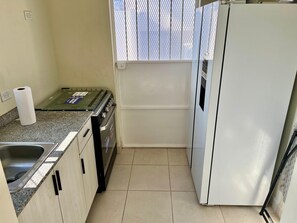 A compact kitchen with a stove, sink, and refrigerator. - Beach House in Playa Dorada with Bay Club and Swimming Pools | WIFI | Pets (Vacamonte)