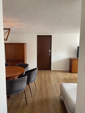 A room with a wooden dining table, grey chairs, a wooden wardrobe, a wooden door, a bed, and a small wooden cabinet. - WorldCup2026 7km + Parking + Security 24/7 Big Apartment near Frida Kahlo house. (Ciudad de México)