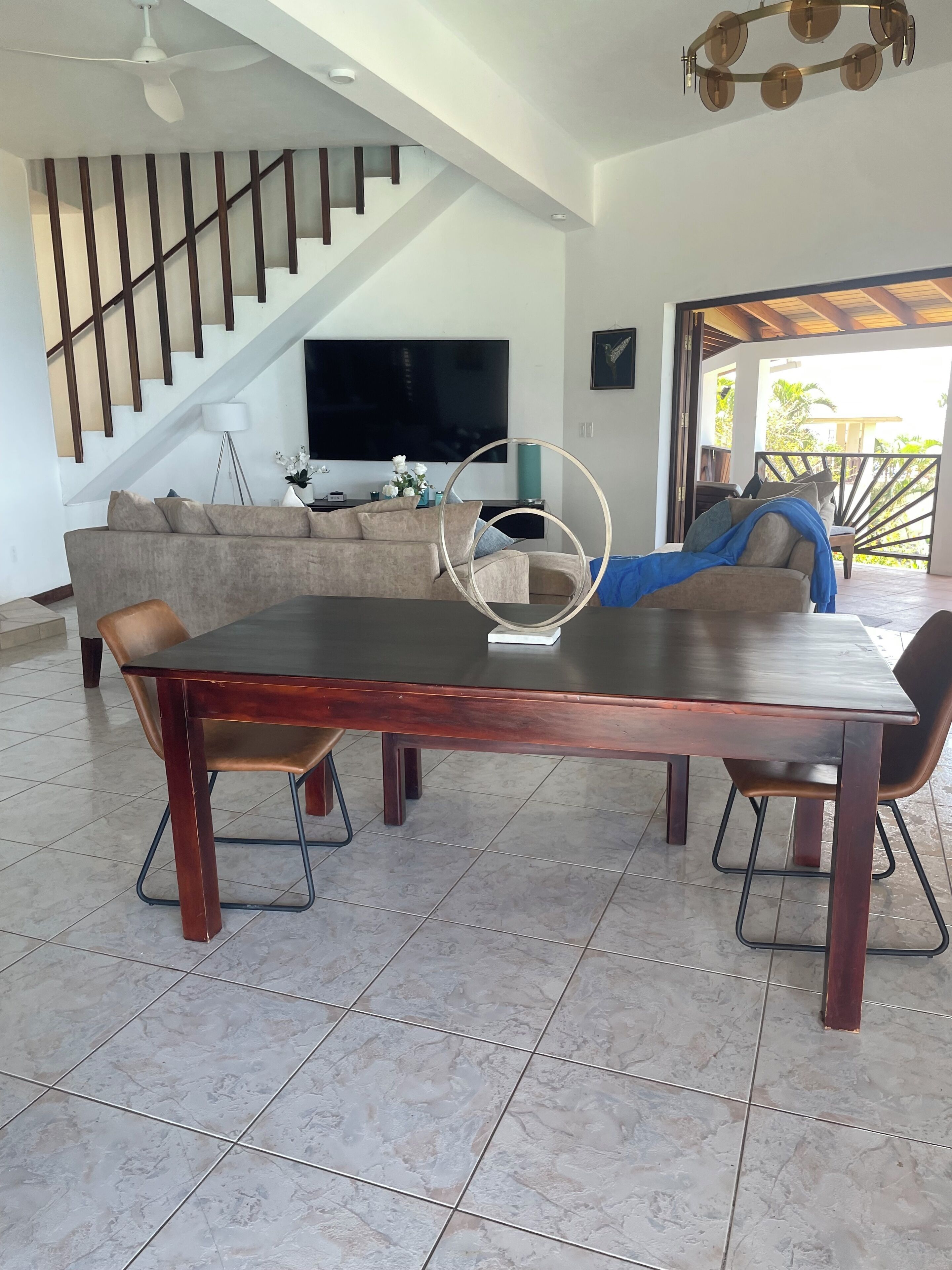 A modern living room with a dining table, sofa, and a staircase.
