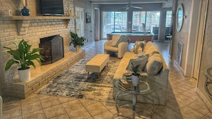 A living room with a fireplace, sofa, coffee table, and a pool table in the background. - Inlet Life -Private Dock/Pool- (Murrells Inlet)