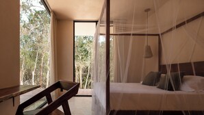 Ein Schlafzimmer mit einem Bett, einem Sessel und einem Fenster mit Blick auf Bäume.