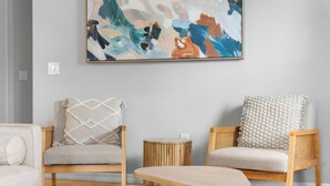Una stanza con due sedie di legno, un tavolino rotondo e un grande quadro astratto appeso al muro.