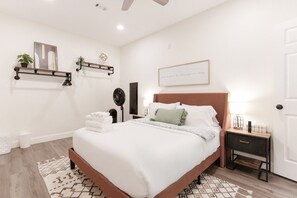 A neatly arranged bedroom with a bed, bedside tables, a wall-mounted shelf, and a framed quote on the wall. - 7BR Luxury Home 15 Min to Universal Studios - Home Theater, Game Room, Sleeps 16 (Frisco)