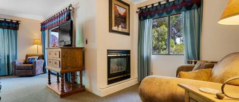 A living room with a fireplace, a sofa, a wooden dresser, and a television.
